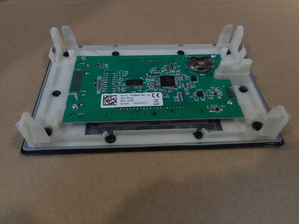 Grüne Leiterplatte mit elektronischen Bauteilen und Halterungen, montiert auf einem weißen Gehäuse. Produziert von Remeha, zur Verwendung in technischen Anwendungen.